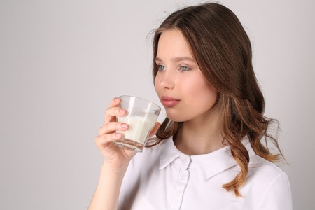 Girl drinking milk, girl in white T-shirt, high fashion look, healthy lifestyle, beautiful girl, smiling girl, isolated, perfect make-up, big lips, model in studio, close up, white backgroundの写真素材