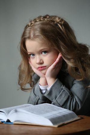 Little girl with makeup and a book, happy childhood, high fashion look, little girl, happy family, cute baby, beautiful girl, blonde girl, isolated, baby in studio, long hair, close up, gray backgroundの写真素材