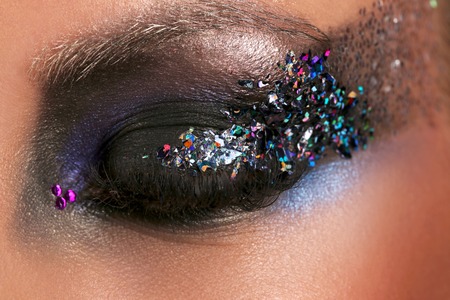 Model's eye with makeup and colorful crystals, girl's eye, eyeshadow and colorful crystals, perfect make up, model, big eyes, long eyelashes, eye with black fashion make-up, close upの写真素材
