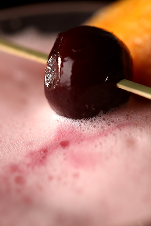 Cherry on skewer above the cocktail. Close upの写真素材