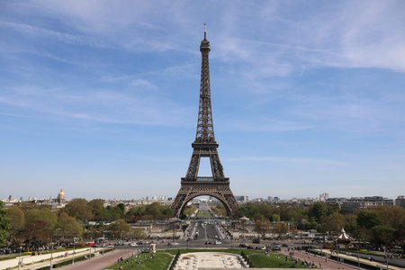 Eiffel Tower and there are a lot of tourists, cars and trees near it