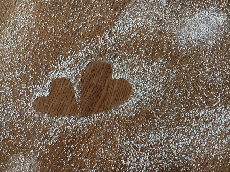 Close-up of two hearts made from sugar powder on the wooden table backgroundの写真素材