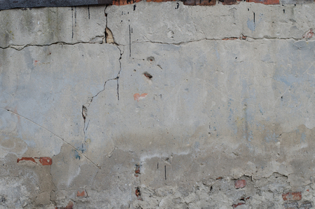old grey concrete garage wall with red bricks and cracks abstract backgroundの写真素材