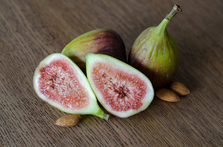 Close-up of fresh figs with one slised ripe fig on a wooden table backgroundの写真素材