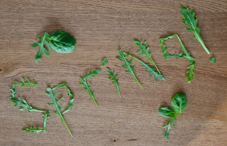 word Spring made of rucola and spinach leaves on wooden backgroundの写真素材