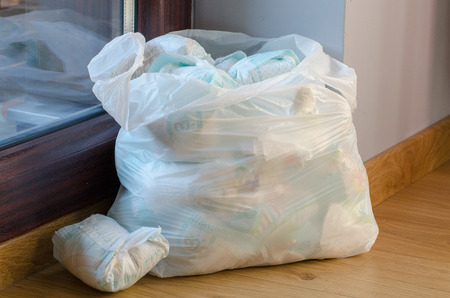 a bag full of dirty baby's  diapers standing on the floor side point viewの写真素材