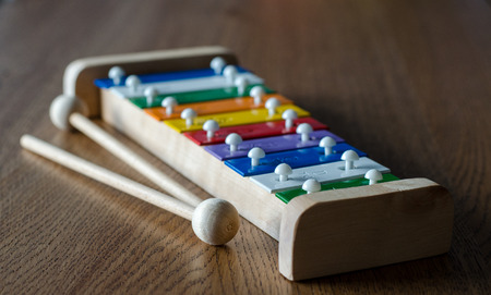 Rainbow coloured xylophone on wooden background angle view. metallophone with soft focus effectの写真素材
