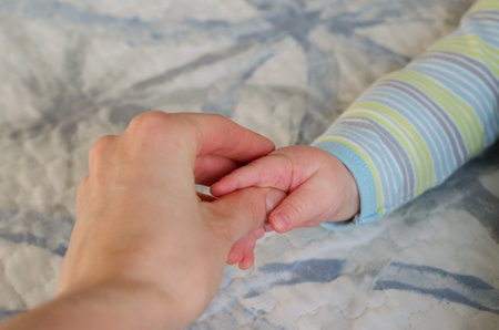 Close-up of mom hand holding baby hand