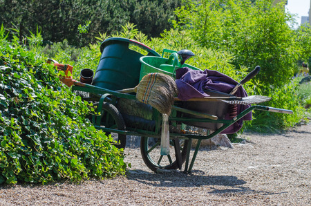 A garden cart with a broom, rake, watering can and buckets in botanical garden in Wroclaw, Poland.の写真素材