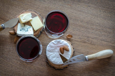 Two glass of red wine with few pieces of cheese at wooden background. top viewの写真素材