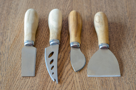 Four cheese knives on wooden backgroundの写真素材