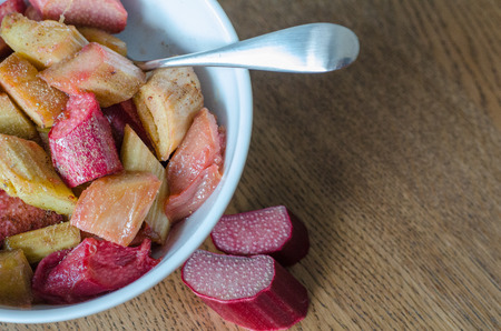 White bowl with stewed rhubarb and small spoon on wooden background. close-up.の写真素材