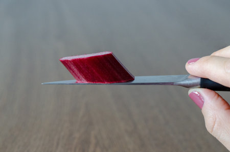 Slice of rhubarb lying on knife blade in woman's hand. close-up
