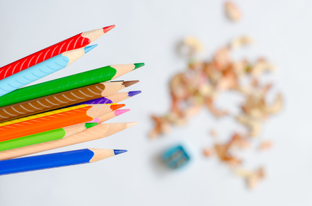 Colored pencils against blurred shavings on white background.の写真素材