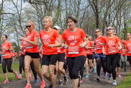 Huge group of women in orange t-shirts with numbers. Marathon in the park in spring. Wroclaw, Poland - April 7, 2019.のeditorial素材