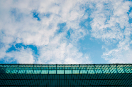 Blue sky with white clouds and glass wall of geometric pattern background. copy space for textの写真素材