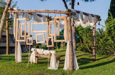 Rustic Wedding Photo booth Set-up outside. Wooden bench with hanging wooden frames as background.の写真素材