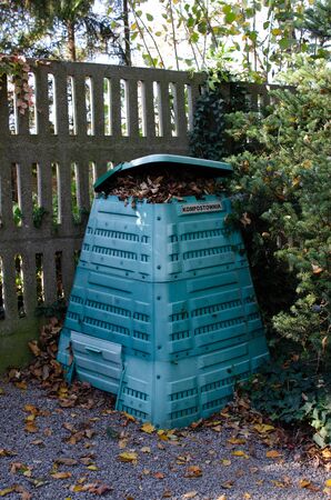 Full Outside plastic compost container with leaves and branches. Text on polish is Compost bin.の写真素材