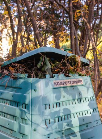 Full Outside plastic compost container with leaves and branches. Text on polish is Compost bin.の写真素材