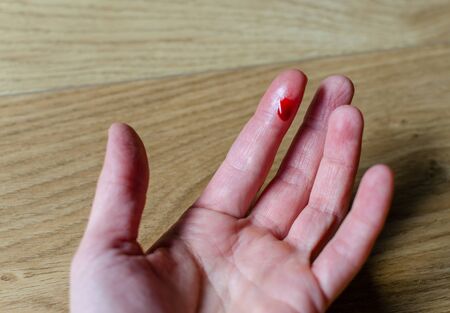 Finger with red blood drop caused by accident, knife cut.の写真素材
