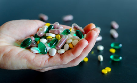 Lots of different medicine drugs, pills, tablets, capsules in woman hand on black matte background....