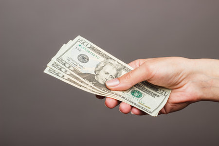 Female hand holding a 20 Dolar on a dark 