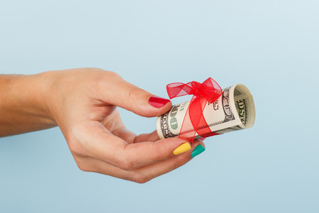 woman's hand is holding money on the blue background.. Dollar billsの写真素材