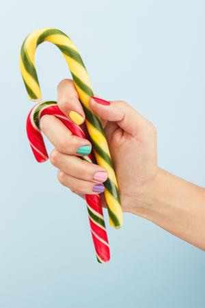 colorful candies in woman's hand on the blue backgroundの写真素材