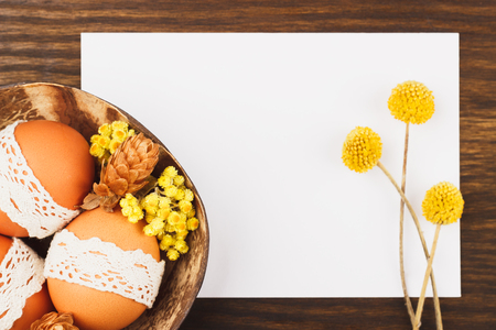 Easter eggs with decorations in the bowl, wooden backgroundの写真素材