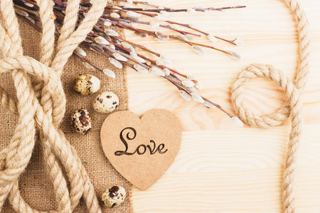 Easter eggs with decorations and willow twigs, wooden background
