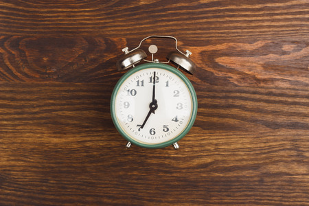 Green vintage alarm clock on the wooden backgroundの写真素材