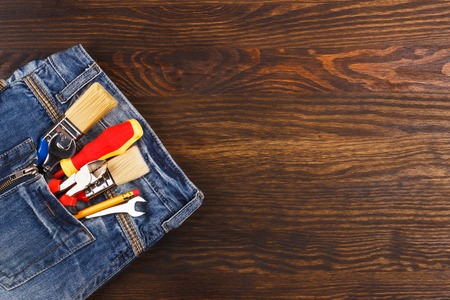 Different construction tools in the denim pocket, wooden backgroundの写真素材