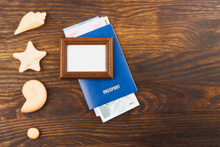 Wooden frame, passport with money and decorations from seashells on the wooden background