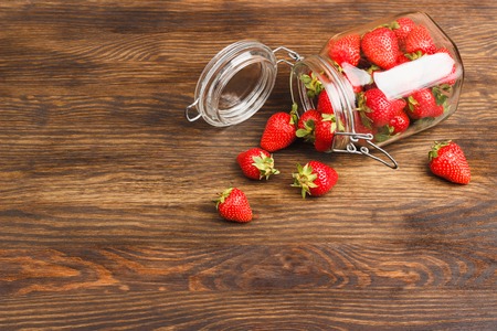 Red strawberries inside the glass jar on the wooden backgroundの写真素材