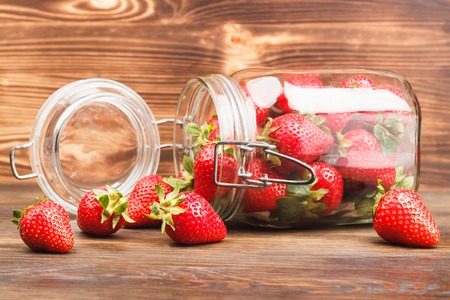 Red strawberries inside the glass jar on the wooden backgroundの写真素材