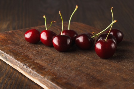 Few red cherries on the old wooden board with blank copy space area for text or sloganの写真素材