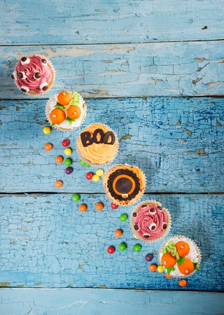 Halloween cupcakes with decorations: orange pumpkins made from confectionery mastic, soft focus backgroundの写真素材