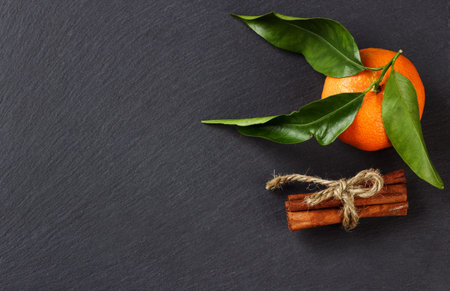 Fresh orange mandarin and cinnamon on the black slate stone background, with copy spaceの写真素材