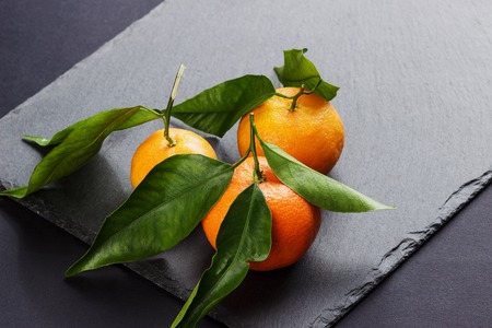 Fresh orange mandarin on the black slate stone background, with copy spaceの写真素材