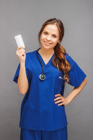 Woman doctor in the blue medical uniform and with stethoscope, gray backgroundの写真素材
