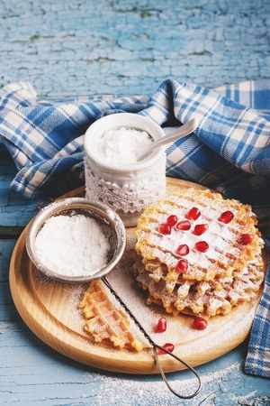 Few waffles, a sugar bowl and sugar powder in the strainer, soft focus backgroundの写真素材