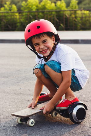 Young boy with a black gyro scooter and skateboard, outdoors, soft focus backgroundの写真素材