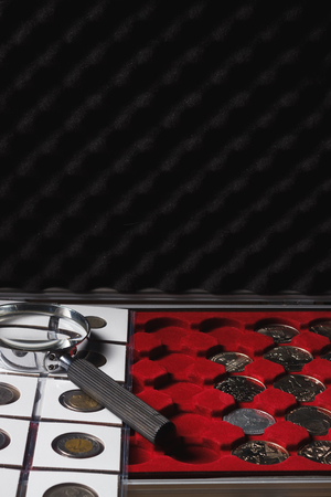Box with collectible coins in the cells and a page with coins in the pockets, soft focus backgroundの写真素材