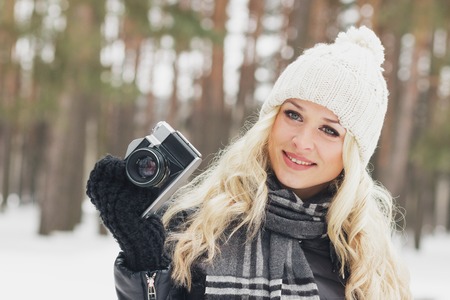 Young woman with an old camera in the hands in the pine tree forest, soft focus backgroundの写真素材