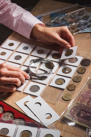 Old collectible coin in the paper pocket in the woman's hand, soft focus backgroundの写真素材