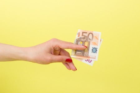 Fifty euro in the woman's hand, on the yellow backgroundの写真素材