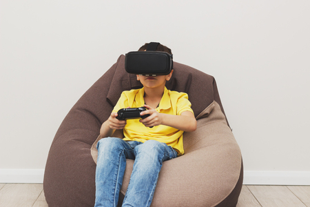 Boy plays game with virtual reality glasses indoors. Digital vr deviceの写真素材