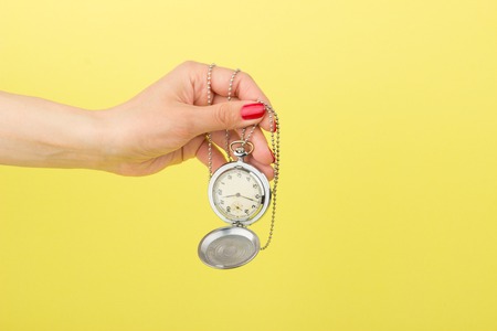 Pocket's clock in the woman's hand on the yellow backgroundの写真素材