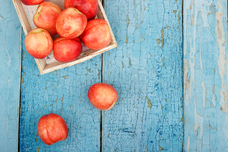 Ripe red peaches in the tray on the blue wooden table, top viewの写真素材