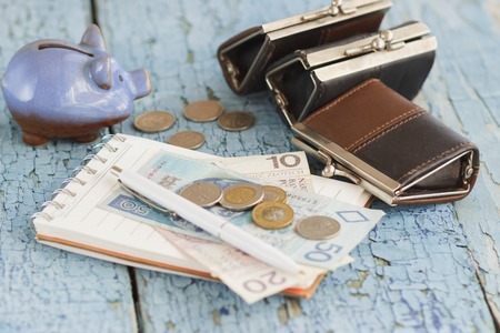 Polish zloty, wallets, pocket clock, notebook and calculator on the wooden background, soft focus backgroundの写真素材
